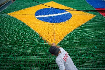 Eine Person gibt der hängenden Dekoration zur Feier der Fußballweltmeisterschaft 2026 auf der Rua 03 im Viertel Alvorada in Manaus, der Hauptstadt des brasilianischen Bundesstaates Amazonas, den letzten Schliff.