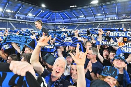 Die Zuschauer im Stadion feiern und halten Schals in die Höhe.