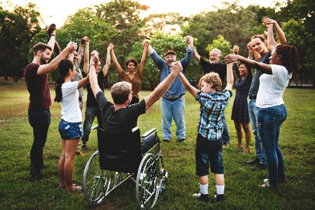 Menschen, die Vielfalt, repräsentieren, stehen im Park und fassen sich an der Hand