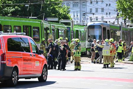 Einsatzkräfte von Polizei und Feuerwehr stehen nach einem Unfall neben zwei Stadtbahnen.