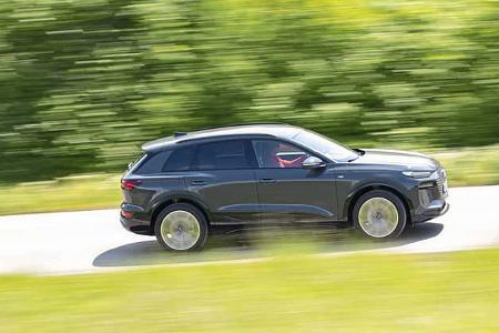 Audi Q6 SUV e-tron quattro fährt auf einer Landstraße, Seitenansicht, grüne Umgebung, Bewegungseffekt.