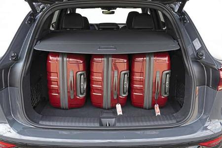 Audi Q6 SUV e-tron quattro Kofferraum mit vier roten Koffern, Heckansicht, Gepäckraum unter Abdeckung.