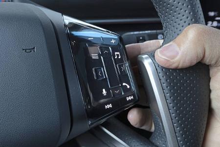 Detailaufnahme des Multifunktionslenkrads eines BMW IS 30x drive mit beleuchteten Bedientasten und Daumensteuerung.