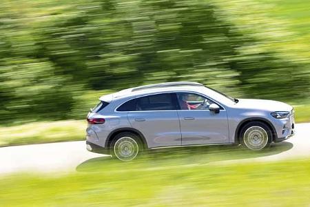 Mercedes GLC 400 4matic EQ fährt auf einer Landstraße, Seitenansicht, grüne Landschaft im Hintergrund.