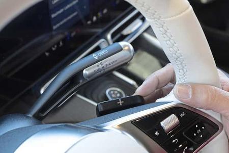 Detailaufnahme des Lenkrads und des Schalthebels eines Mercedes GLC 400 4matic EQ. Zu sehen sind Schaltwippen, Bedienelemente und der elektronische Wählhebel.