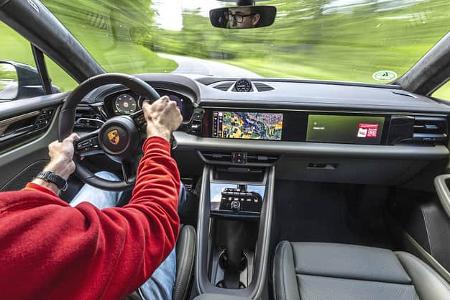 Innenraum und Cockpit eines Porsche Macan 4S während der Fahrt, Fahrer am Steuer, moderne Digitalanzeigen und Navigationssystem sichtbar.