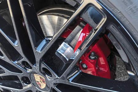 Detailaufnahme einer schwarzen Leichtmetallfelge mit Porsche-Logo und rotem Bremssattel des Porsche Macan 4S.
