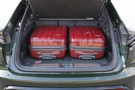 Der geöffnete Kofferraum eines Porsche Macan 4S mit zwei roten Hartschalenkoffern.