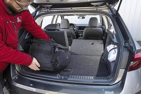 Kofferraumansicht eines Skoda Fabia 1.0 TSI mit umgeklappter Rückbank, Person lädt eine schwarze Tasche ein.