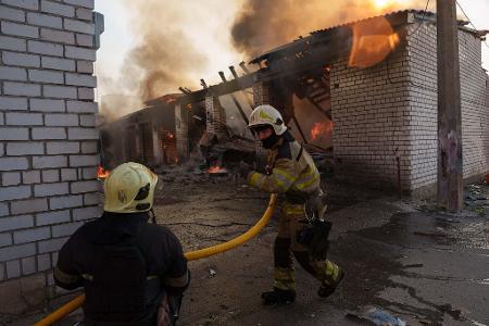 Rettungskräfte löschen ein Feuer in einer Kiewer Autowerkstatt, die durch einen russischen Angriff beschädigt wurde.