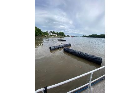 Kunststoffrohre treiben auf dem Rhein