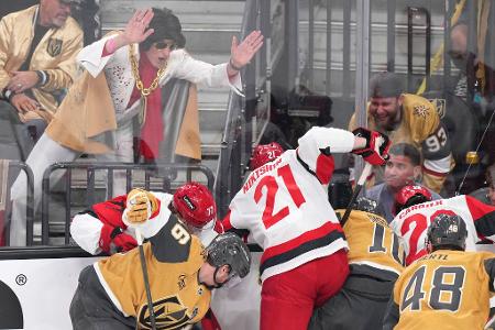 Ein Elvis-Imitator schlägt auf die Scheibe, während die Spieler um den Puck kämpfen.