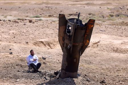 Ein Mann betrachtet das Wrack einer Rakete, die nach einem iranischen Angriff im Westjordanland aus dem Boden ragt.