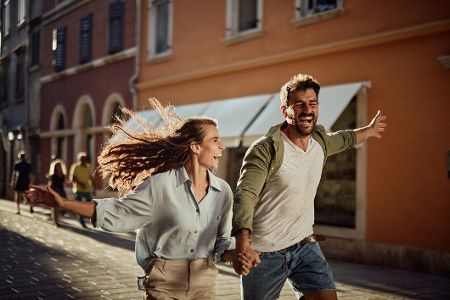 Glückliches Pärchen rennt durch die Straßen einer Stadt