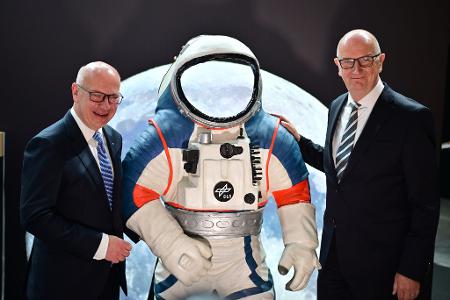 Kai Wegner (l, CDU), Regierender Bürgermeister von Berlin, und Dietmar Woidke (SPD), Ministerpräsident von Brandenburg, stehen neben einem Modell eines Weltraumanzuges.
