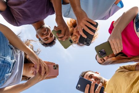Teenager stehen im Kreis und haben alle ein Handy in der Hand