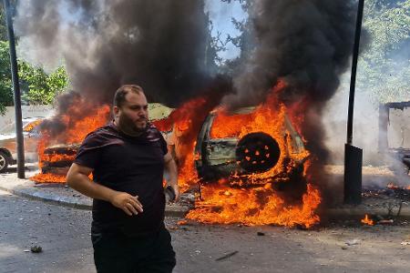 Ein Mann läuft vor brennenden Autos, die bei einem israelischen Luftangriff in der libanesischen Hafenstadt Sidon in Brand geraten sind.