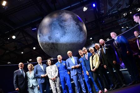 Bundeskanzler Friedrich Merz (6.v.l, CDU) steht unter anderem mit den beiden Esa-Astronauten Alexander Gerst (5.v.l) und Matthias Maurer (7.v.l) während eines Rundgangs auf der Internationalen Luft- und Raumfahrtausstellung (ILA).