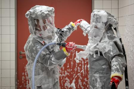 Louise Götze (l) und Ursula Pfitzner, Intensivpflegerinnen und Koordinatorinnen auf der Sonderisolierstation der Charité, desinfizieren sich während eines Pressetermins nach der Rückkehr aus dem Patientenzimmer in der Schleuse mit einer Schaumlösung.