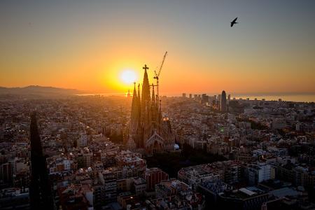 Im Gegenlicht der aufgehenden Sonne ist das Kreuz aus Deutschland auf der Spitze des höchsten Turms der Basilika Sagrada Família in Barcelona gut zu erkennen. (Archivbild)
