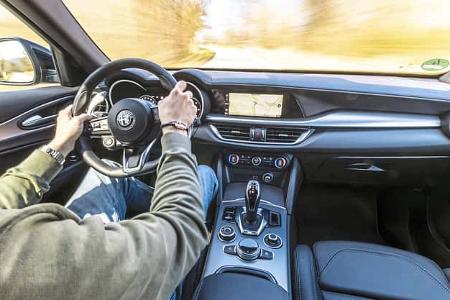 Innenraumaufnahme eines Alfa Stelvio 2.0 Diesel während der Fahrt, Blick aus der Fahrerperspektive auf Lenkrad, Armaturenbrett und Mittelkonsole.
