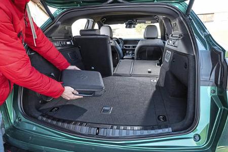 Der Kofferraum eines Alfa Stelvio 2.0 Diesel mit umgeklappter Rückbank. Eine Person legt eine Tasche in den Laderaum.