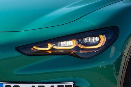 Detailaufnahme des Frontscheinwerfers und Kotflügels eines Alfa Romeo Stelvio 2.0 Diesel in grün-metallic Lackierung. Das LED-Tagfahrlicht ist eingeschaltet und ein Teil des Kühlergrills sowie das vordere Kennzeichen sind sichtbar.