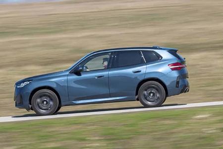 BMW X3 xDrive 20d in Seitenansicht auf Landstraße, dynamische Fahrt, blauer SUV, Fahrer sichtbar.