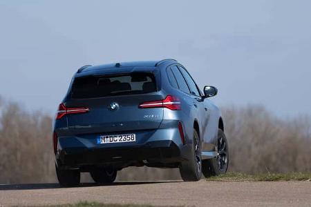 BMW X3 xDrive 20d SUV von hinten auf einer Landstraße, blauer Lack, Nummernschild sichtbar, Bäume im Hintergrund.