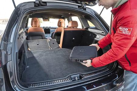 Mercedes GLC 220d 4Matic, geöffnete Heckklappe, Blick in den Kofferraum mit umgeklappter Rückbank, Person legt Tasche hinein.