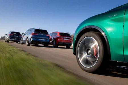 Vier SUV-Modelle (Mercedes GLC 220d 4Matic, BMW X3 xDrive 20d, Alfa Romeo Stelvio 2,0 Diesel, VW Tiguan 2.0 TDI) fahren auf einer Landstraße, fotografiert aus niedriger Perspektive mit Fokus auf das Vorderrad des Alfa Romeo Stelvio. Aufnahme auf dem Flugplatz Gmünd.