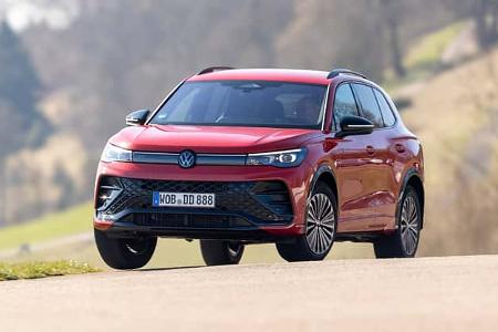 VW Tiguan 2.0 TDI in Rot auf Landstraße, Frontalansicht, SUV-Modell, Fahrzeug in Bewegung, unscharfer Hintergrund.