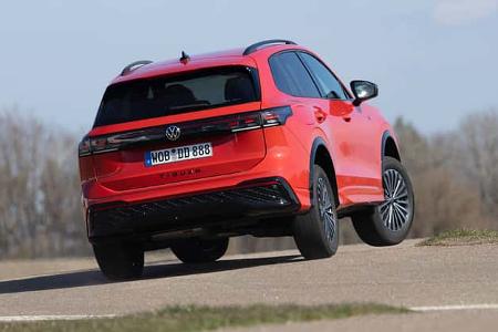 VW Tiguan 2.0 TDI in Rot, fotografiert von hinten während einer dynamischen Fahrszene auf Asphalt.