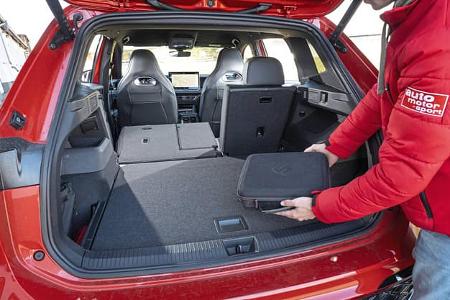 Der Kofferraum eines VW Tiguan 2.0 TDI mit umgeklappter Rückbank, ein Mann legt eine Tasche hinein.