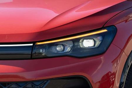 Detailaufnahme des Frontscheinwerfers eines VW Tiguan 2.0 TDI in Rot. Die Aufnahme zeigt die moderne LED-Lichtsignatur und einen Teil des Kotflügels sowie die Motorhaube.