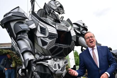 Verteidigungsminister Pistorius scherzt neben einer Transformer-Figur bei der ILA 2026 in Berlin.