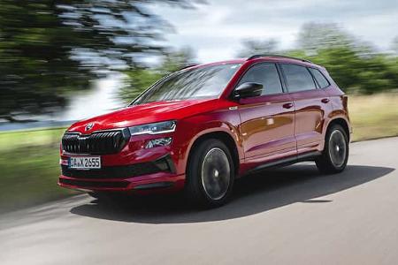 Skoda Karoq 4x4 in Rot fährt auf einer Landstraße, dynamische Außenaufnahme, Fahrzeug in Bewegung.