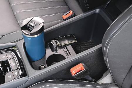 Detailaufnahme der Mittelkonsole eines Skoda Karoq 4x4 mit Getränkehalter, Autoschlüssel und Thermobecher.
