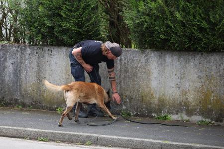 Ein Polizist sucht mit einem Spürhund nach Hinweisen.