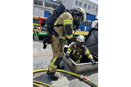Ein Trupp der Feuerwehr Bremerhaven geht unter Atemschutz über eine Einstiegsluke in den Maschinenraum des Binnenschiffes vor, um den Brand zu bekämpfen und den betroffenen Bereich zu kontrollieren.