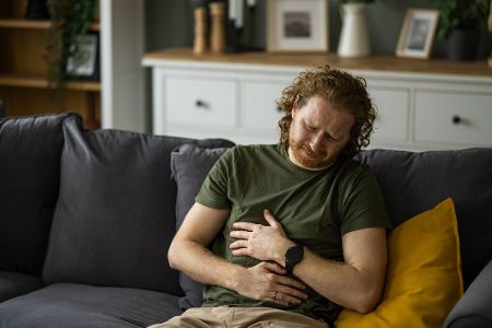 Mann hält sich den Bauch vor Schmerzen