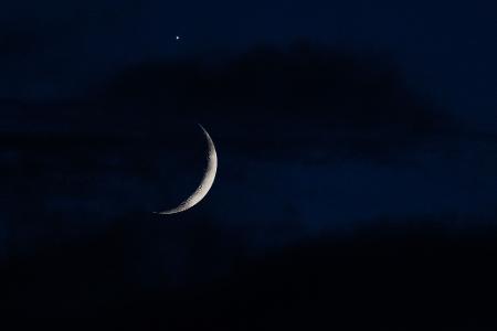 Der sichelförmige Mond wird am Abend hinter Wolken über Köln von der Venus (oben) begleitet.