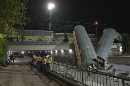 Zwei Waggons eines Güterzugs liegen auf einer Straße in München, nachdem sie von einer Brücke gestürzt sind.