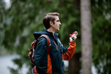 Junger Mann mit Wanderrucksack und Inhalator