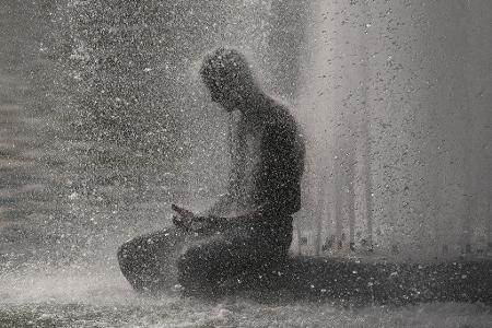 Eine Person erfrischt sich während der Hitzewelle in Paris in einem Brunnen in der Nähe des Eiffelturms.