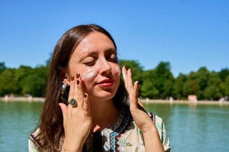 Frau cremt sich Gesicht mit Sonnenmilch ein