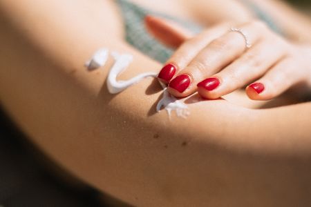 Frau cremt sich die Haut mit Sonnencreme ein