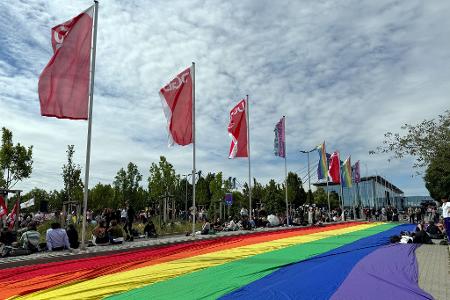 Eine übergroße Regenbogenfahne liegt ausgebreitet neben einer Kundgebung des DGB in Erfurt