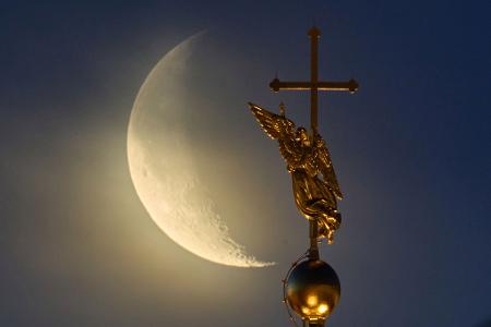 Vor dem Mond ist das Wahrzeichen der Stadt St. Petersburg, eine Wetterfahne in Form eines Engels, zu sehen.