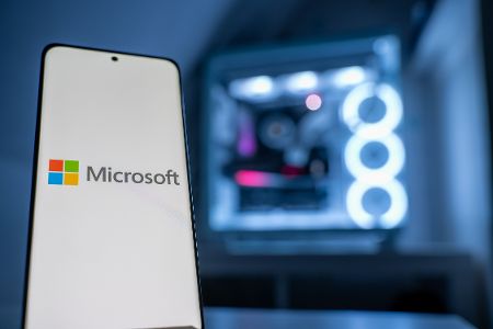 Handy mit Microsoft-Logo und -schriftzug vor einem Computer